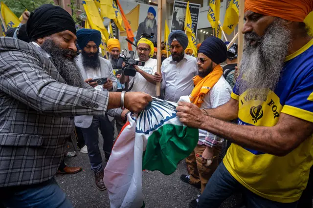 Two protestors try to rip the Indian flag after setting it on fire outside of the Consulate General of India Office during a protest for the recent shooting of Shaheed Bhai Hardeep Singh Nijjar in Vancouver on Saturday, June 24, 2023.