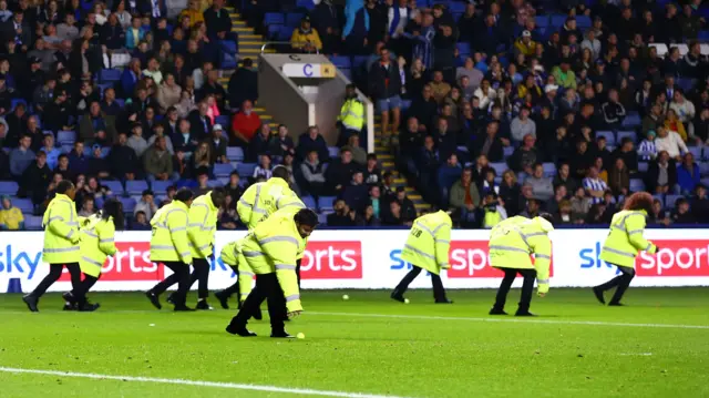 Stewards collect tennis balls off the pitch at Hillsborough