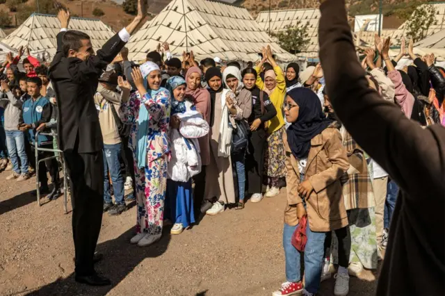 Students attend an assembly outside classroom tents at a make-shift school in the earthquake-hit village of Asni in al-Haouz province in the High Atlas mountains of central Morocco on September 18, 2023.