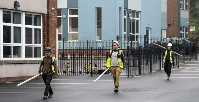 Builders carry materials at a school