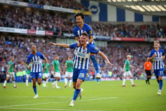 Mitoma jumps on the back of Ferguson as they celebrate the latter's goal together.