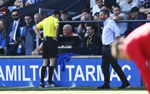 Referee Kevin Clancy checks an incident using VAR