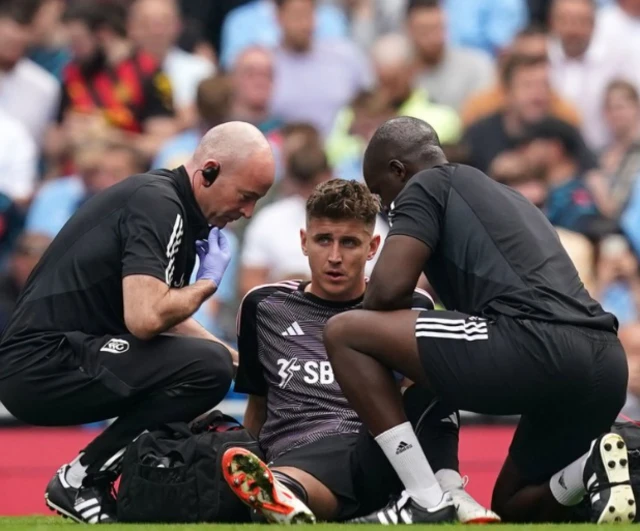 Tom Cairney lays on the floor alongside physios