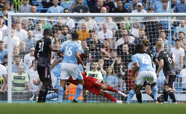 Player stand and watch as the ball heads towards a diving Leno in goal.