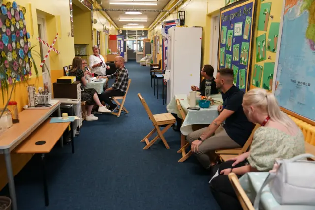 Staff sitting in a temporary "staff room" in a corridor in a school in Leicester