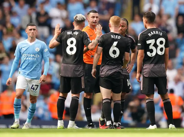 Fulham players surround the referee after an unfavourable decision.