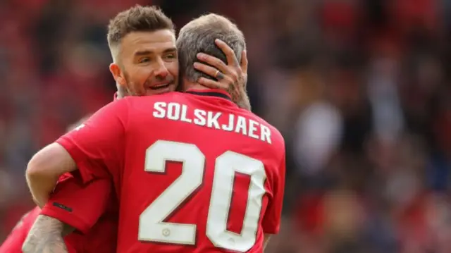 David Beckham and Ole Gunnar Solskjaer embrace at a '99 Legends match