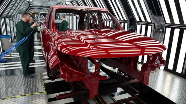 Members of staff check the paintwork on Range Rover bodies as they pass through the paint shop at Jaguar Land Rover’s factory in Solihull,