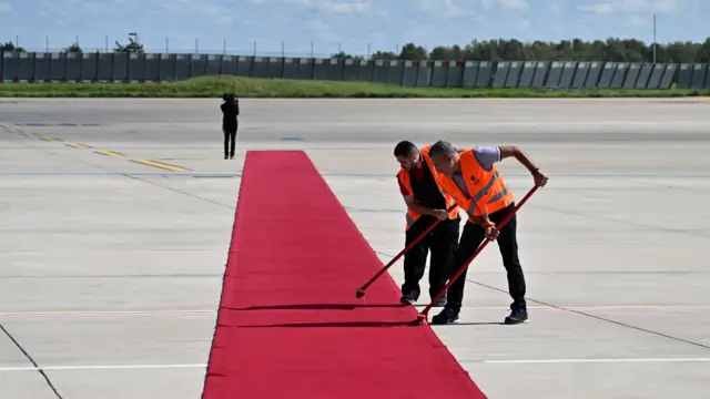 Workers clean the red carpet prior to the arrival of Britain's King Charles III at the Paris-Orly Airport