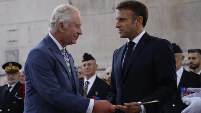 King Charles and Macron look at each other under the Arc de Triomphe