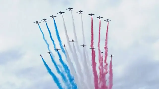 Planes fly in formation in the sky, leaving trails or red, white and blue