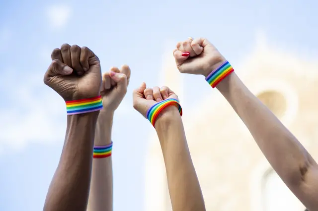 Four fists claiming gay pride rights with gay pride bracelet (stock photo)