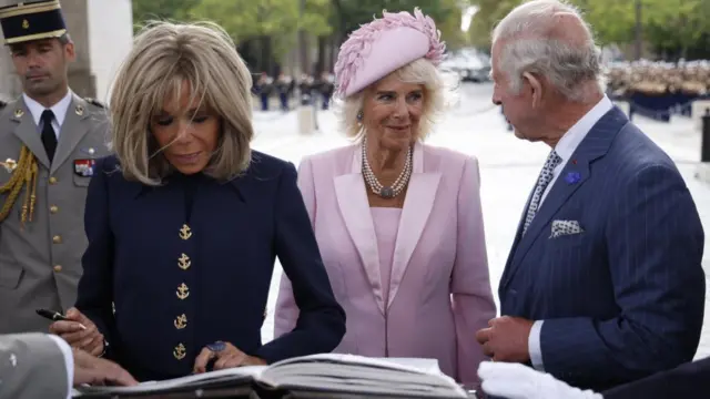 Brigitte Macron writes in a book as the Queen and Charles stand by