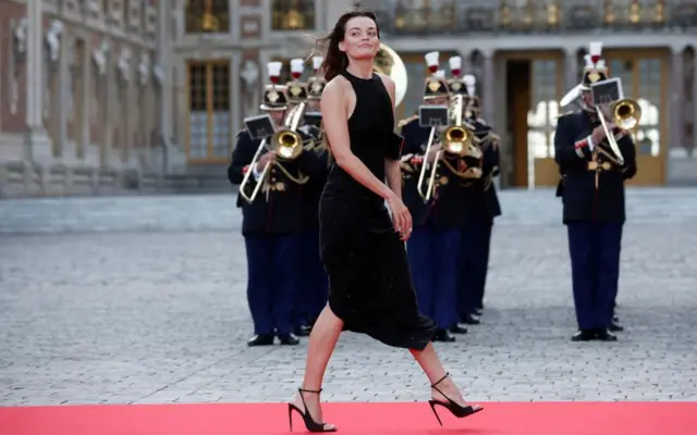 Emma Mackey walks the red carpet in a black cocktail dress