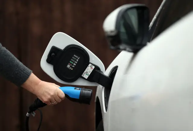 A motorist plugs in their electric car for charging