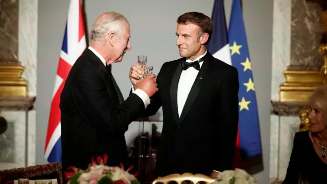 King Charles and Macron hold their champagne glasses in toast