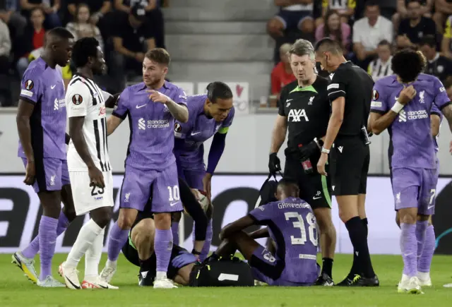 Gravenberch receives treatment as concerned teammates gather around him.