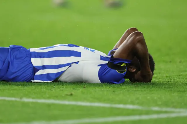 Welbeck holds his hand to his head in disbelief as he lies on the floor.