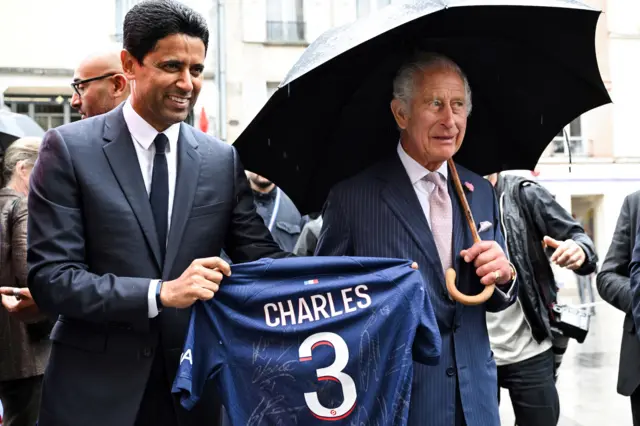 Nasser al-Khelaifi holding a football shirt (left) and King Charles (right)