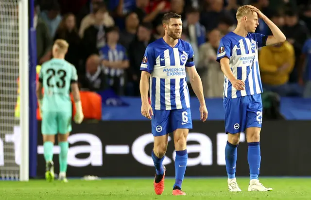 Brighton players stand and hold their heads after conceding again.