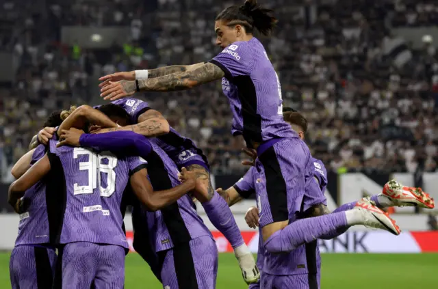 Liverpool players huddle together as Darwin jumps into the middle to celebrate.