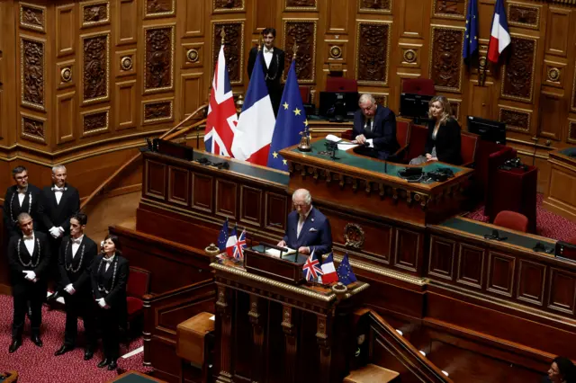 Charles reading on a raised lectern