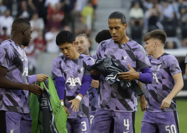 Van Dijk puts on a training bib as Liverpool players gather to warm up.