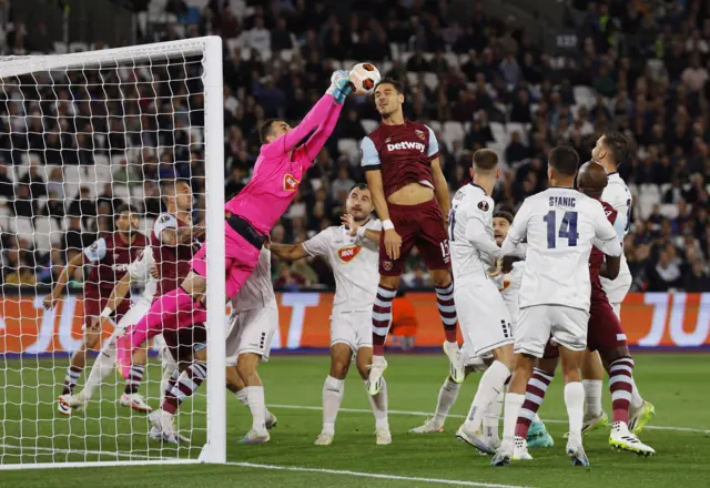 Simic punches the ball clear in a packed penalty area.