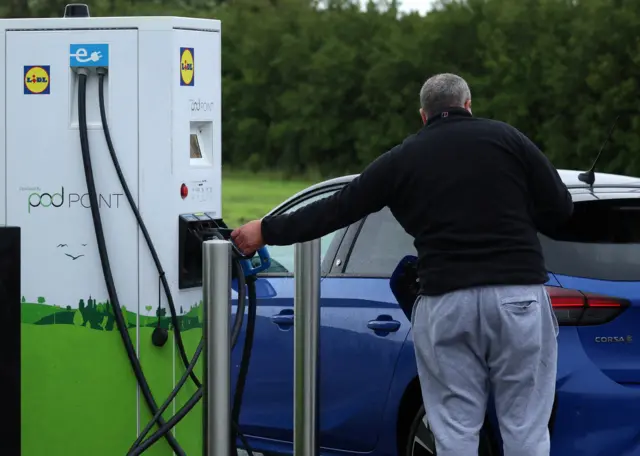 A man plugs in a Vauxhall electric car at a Pod Point electric vehicle rapid charging station in Wallasey, Britain, September 20, 2023.