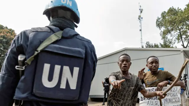 A UN soldier is seen as demonstrators carry a poster against the peacekeeping mission in the Democratic Republic of Congo  - Goma, July 2022