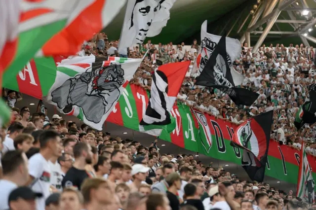 Warsaw fans cheer on their side with big banners in the background depicting the club's colours.