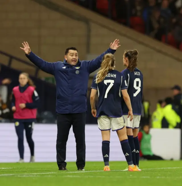 Martinez Losa issues instructions to Weir and Brown on the sideline.