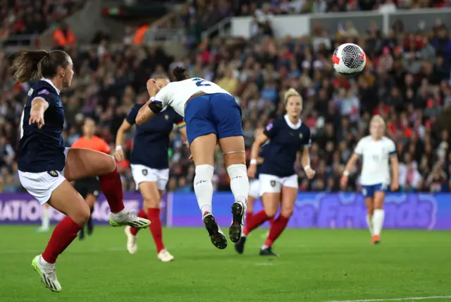 Lucy Bronze dives to head the ball beyond a Scotland defender.