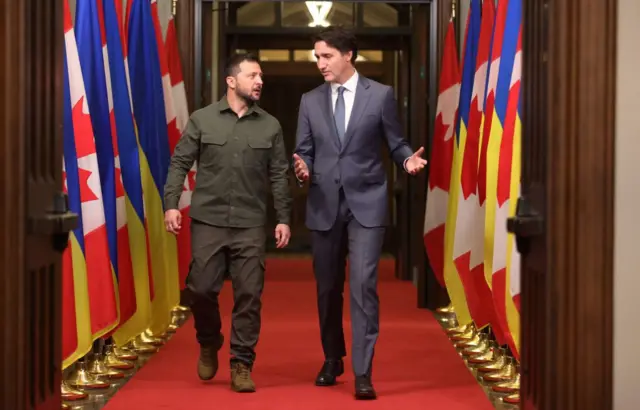 Zelensky and Justin Trudeau walking together near flags