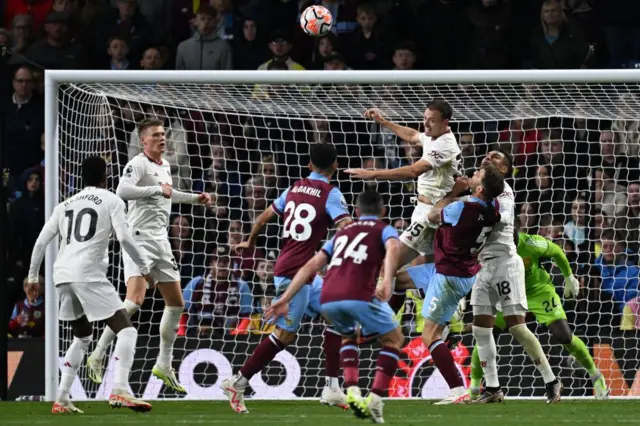 Evans rises high in the box above a crowd to head the ball away for United.