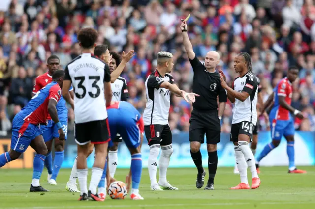 Referee, Paul Tierney shows a yellow card to Joao Palhinha