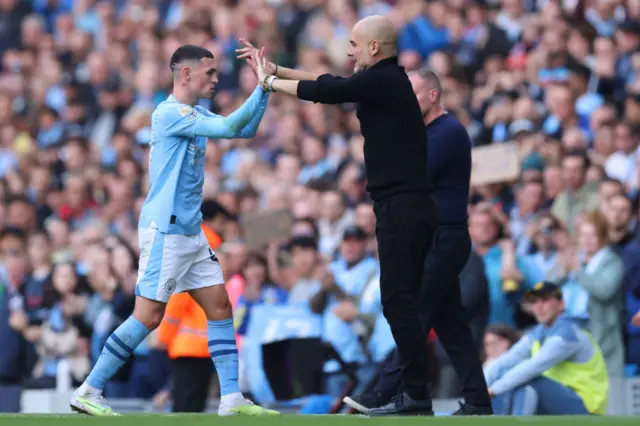 Phil Foden of Manchester City interacts with Pep Guardiola,