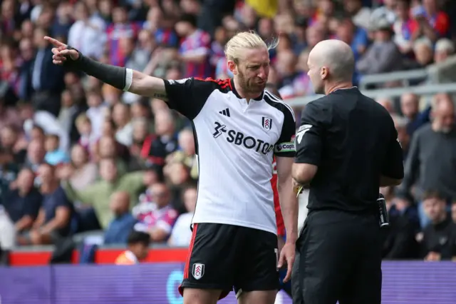 Tim Ream of Fulham argues with the Referee, Paul Tierney after being shown a yellow card