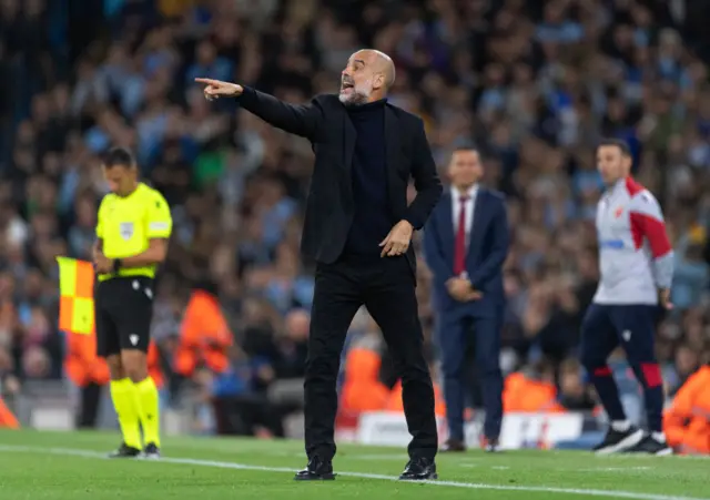 Guardiola shouts and gestures instructions from the sideline.