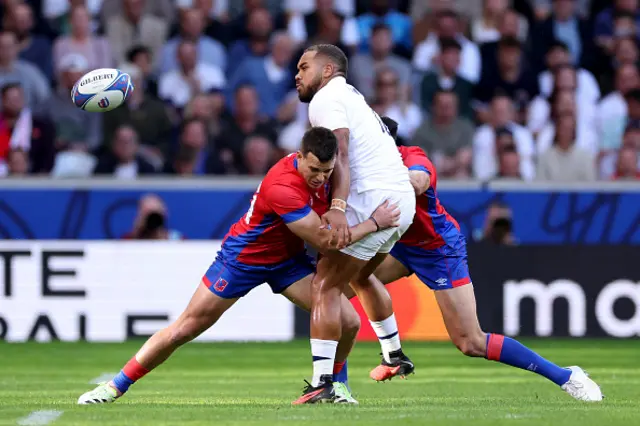 Ollie Lawrence of England offloads the ball as he tackled by Rodrigo Fernandez