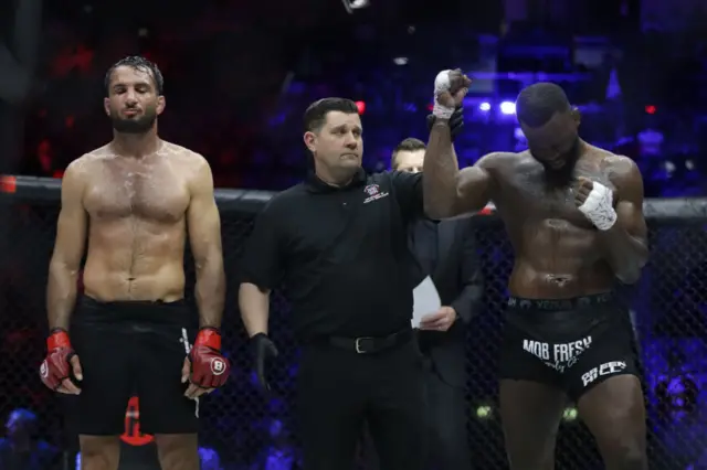 Fabian Edwards has his arm raised by the referee as he stands next to Gegard Mousasi