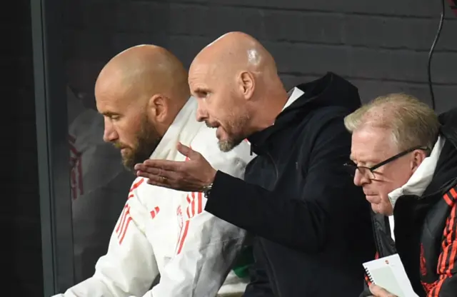 Ten Hag speaks fervently with his assistants on the bench.