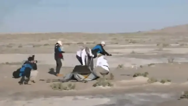 A still of the recovery team taking samples of the soil near where the capsule landed