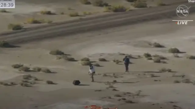 Members of recovery team approach the capsule