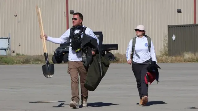 Recovery crew team members returning to base, carrying shovels and other equipment