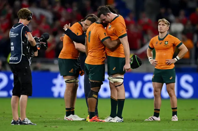 Australian number eight is consoled by substitute Matt Philip as captain Tate McDermott looks on.