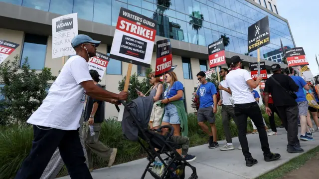 People on a picket line holding placards in support of the writers strike outside of Netflix offices in Los Angeles