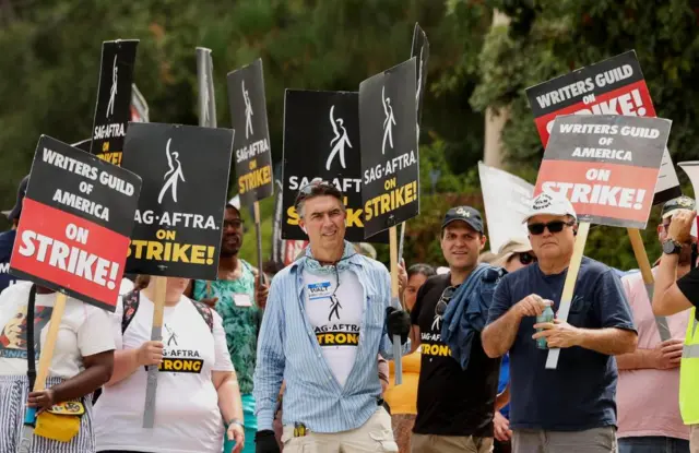 A group of people holding signs saying writers and actors were on strike