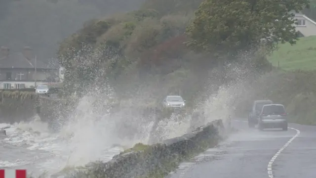 Cars pass waves crashing over a wall into the road in Youghal, Co Cork, 27 September 2023