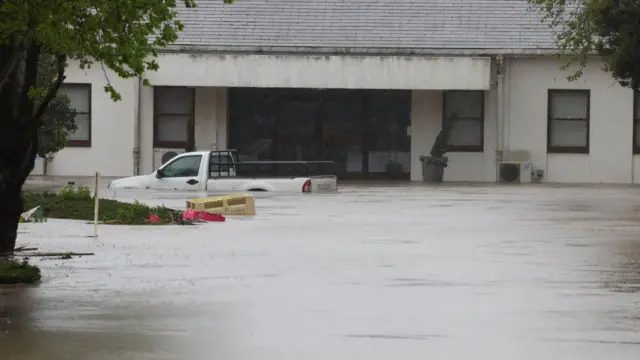 A vehicle partially under water is seen in front of a house following heavy rains, in Elgin, Western Cape, South Africa, September 25, 2023.